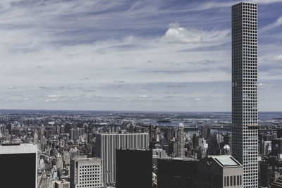 Tall building in city against cloudy sky