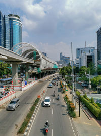 Vehicles on road in city against sky