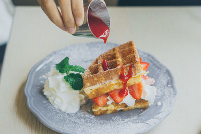 Close-up of hand holding ice cream in plate