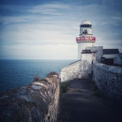 Lighthouse by sea against sky