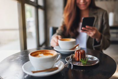 Midsection of woman holding coffee cup on table at restaurant