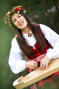 Beautiful musician wearing flowers wreath while playing string instrument