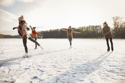 Happy friends ice skating on frozen lake