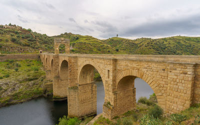 Arch bridge over river against sky