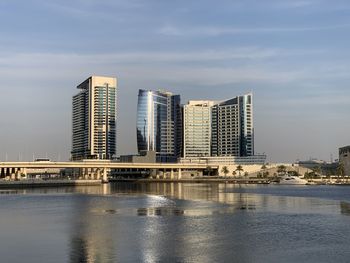 Buildings by river against sky