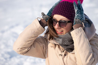Smiling woman wearing sunglasses standing outdoors during winter