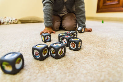 Midsection of boy playing with dices on floor