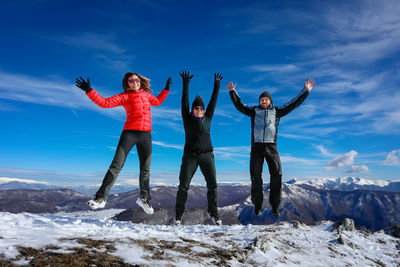 Group of friends jump on snow covered landscape