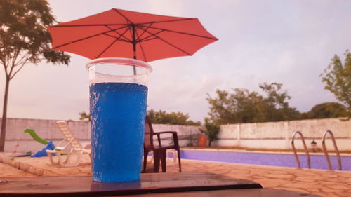 Close-up of table by swimming pool against blue sky