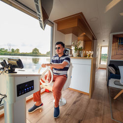 Summer vacation travel on houseboat on a river, man by steering wheel on a river in a houseboat