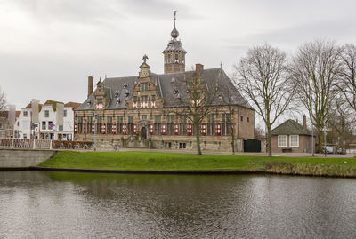 Buildings at waterfront against cloudy sky