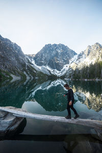 Side view of young man walking on wood over lake