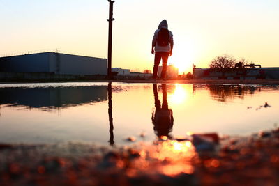 Reflection of silhouette man on river against sky during sunset