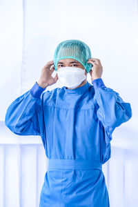 Portrait of smiling doctor wearing mask against white background