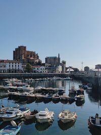 Boats moored in harbor against buildings in city