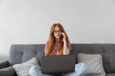 Young woman using phone while sitting on sofa