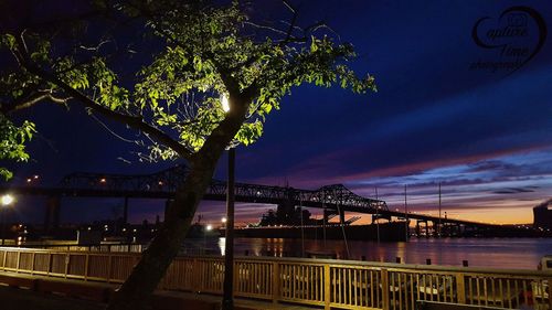 Bridge over river against sky at night