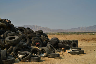 Pile of worn-out black rubber vehicle tires in mojave desert distant mountains pahrump, nevada, usa