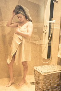 Portrait of young woman standing against wall