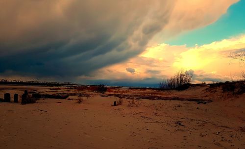 Scenic view of sand dunes against sky at sunset