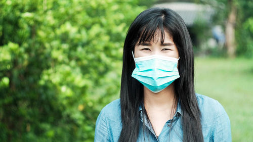 Portrait of beautiful young woman wearing flu mask standing outdoors