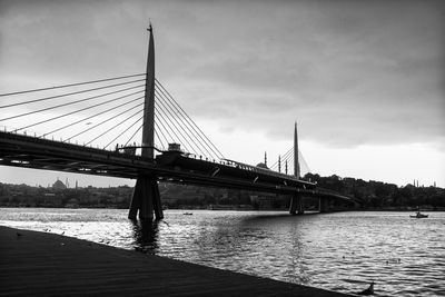 Bridge over river against cloudy sky