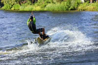 Full length of man splashing water while kiteboarding in sea