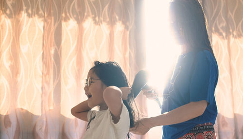 Side view of woman and girl against window