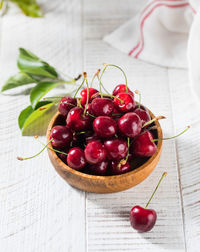 Juicy cherry berries in a wooden bowl on a wooden background.