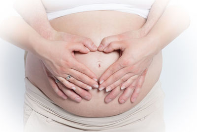 Midsection of woman touching face against white background