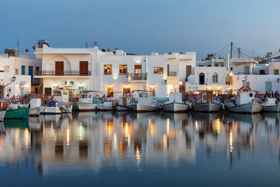 Sailboats moored at harbor by buildings in city