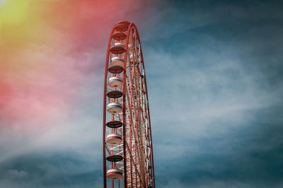 Low angle view of ferris wheel against cloudy sky during sunset
