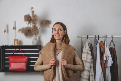 Fashionable millennial woman with sweater on her shoulders stands in fitting room