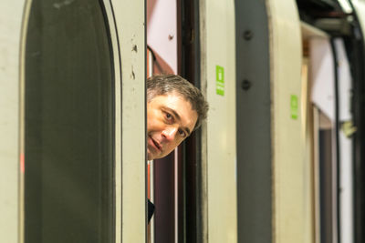 Portrait of man peeking from train window