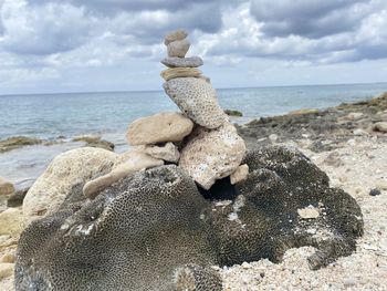 Rocks on shore at beach against sky