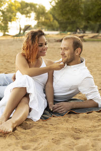 Happy international couple lies on beach. latin woman, caucasian man enjoying vacation. smiling