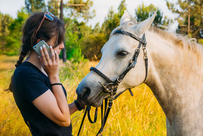 Woman talking on mobile phone by horse 