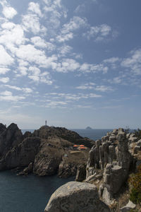 Scenic view of sea by cliff against sky