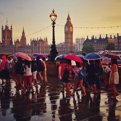 People walking on promenade by big ben during rainy season