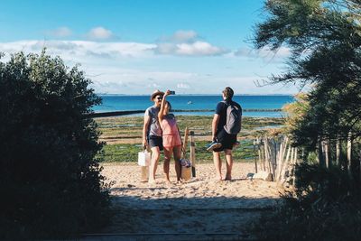 Women standing on shore by sea against sky
