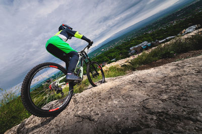 A young cyclist rides off a cliff on his mountain bike against the backdrop of the private sector of