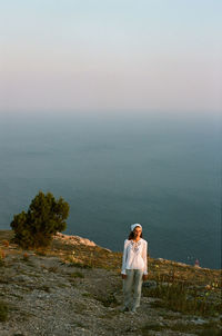 Full length of woman standing by sea against sky