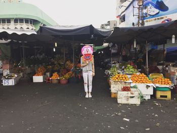 Front view of woman holding cat helium balloon at street market