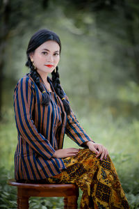 Portrait of young woman standing against plants