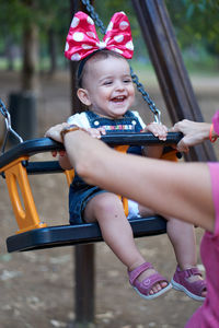 Mother pushing daughter sitting on swing at park