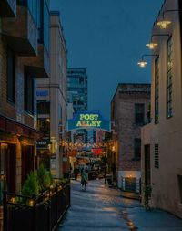 Illuminated street amidst buildings in city at night