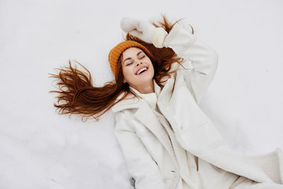 High angle view of smiling woman lying on snow covered land