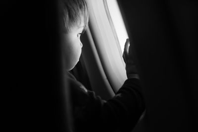 Close-up of boy looking through airplane window