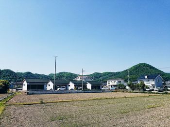 Houses on field against clear blue sky