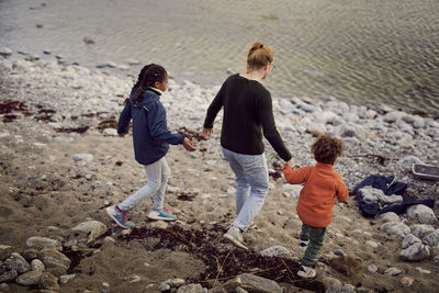 Rear view of mother walking with children at beach